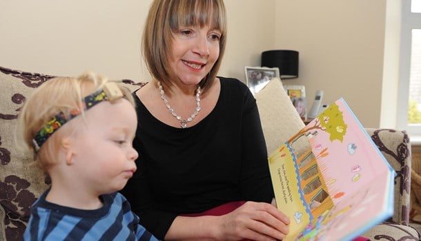 A mother reads a picture book to her toddler who has microtia and atresia.