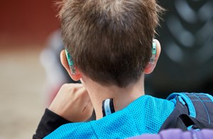 The back of a boy's head who is wearing hearing aids in both ears. 
