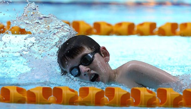 A boy swims laps in a pool lane.