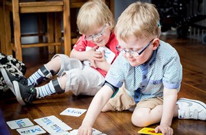 Two young boys play a card learning game on the floor. 