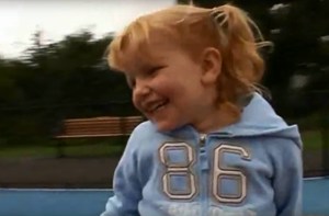 A young girl with pigtails smiles while out at the park.