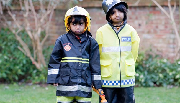 Two boys wearing  policeman and fireman costumes. 