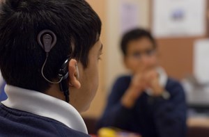 The back of a boy's head who is wearing a cochlear implant.