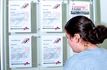 A teen wearing a hearing aids looks a flyers for a careers fair.