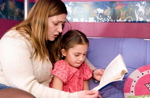 A woman reading to a young girl from a book