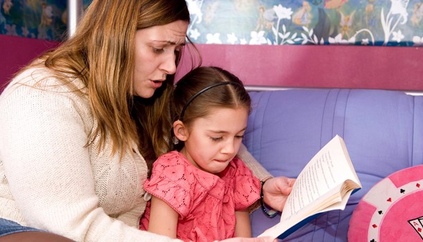 A woman reading to a young girl from a book