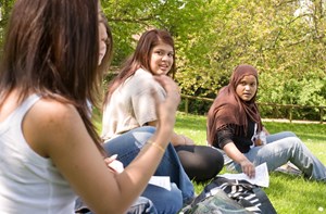 Four young women sat on the grass and signing