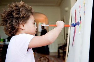 A young child paints at an easel. 