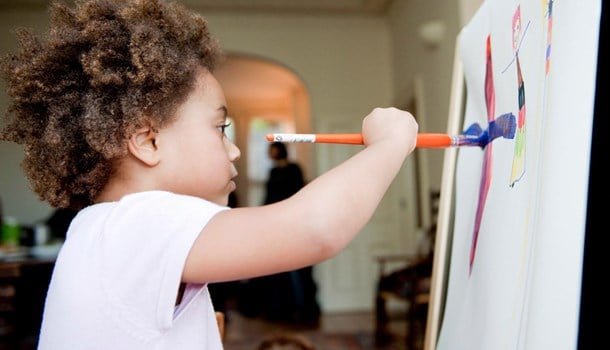 A young child paints at an easel. 