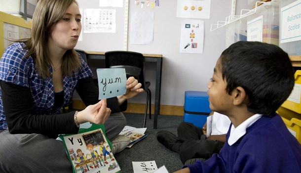A teacher practices phonics with a young student.