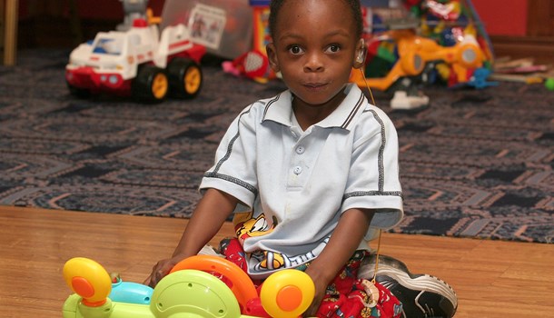 A young boy plays with a toy on the floor. 