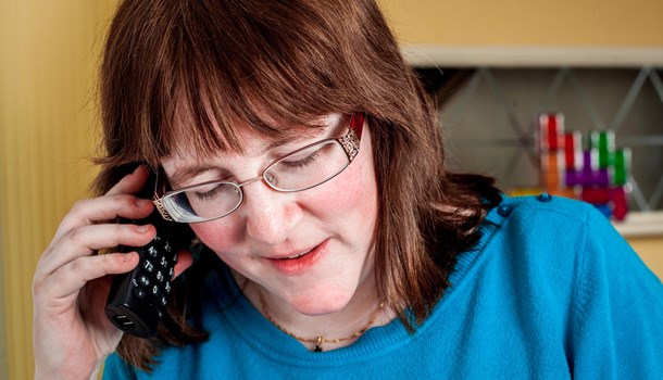 A woman holds a cordless phone to her ear. 