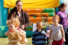 Group of children with faces painted in front of a bouncy castle.