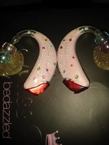 Pink hearing aids decorated with glitter and jewels