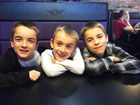 Three boys sitting in a restaurant booth