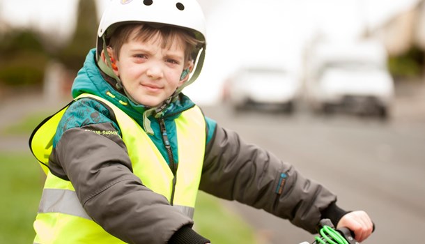 Oliver wearing his hearing aids, a BMX helmet and a high-vis jacket holding his bike.
