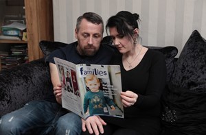 A couple read an issue of the Families magazine on the sofa.