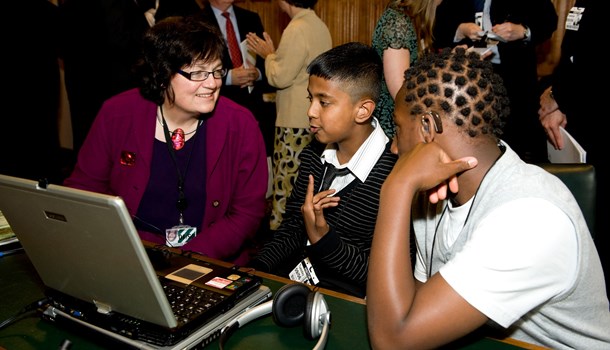 Two teens look at a computer with an adult