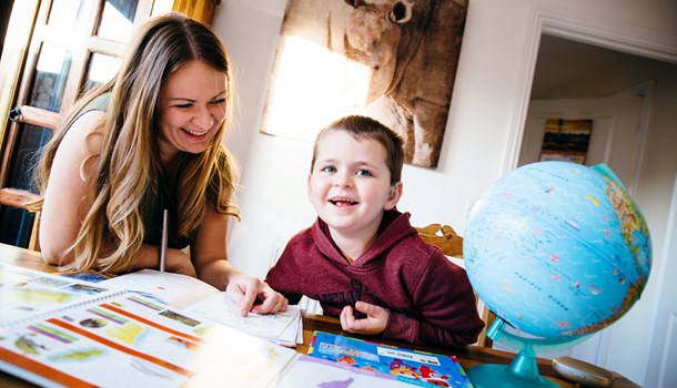 A mum and her young son look at school work at an activity table.