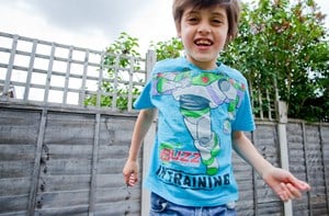 A smiling boy wearing a Buzz Lightyear t-shirt running toward the camera. 