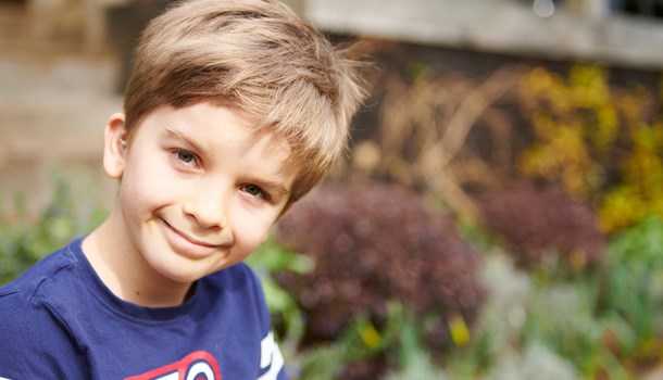 Young boy wearing a blue t-shirt who is outside in a garden