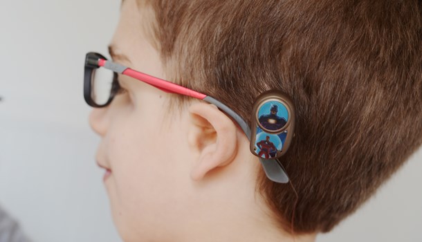 A close-up of a boy's bone conduction hearing implant with superhero sticker decorations. 