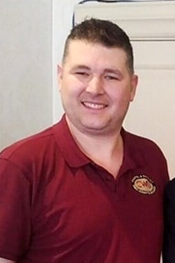 Smiling man wearing a red polo top.