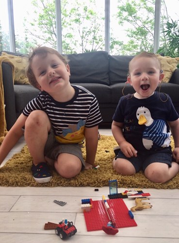 Henry and another child sitting on the floor next to some Lego