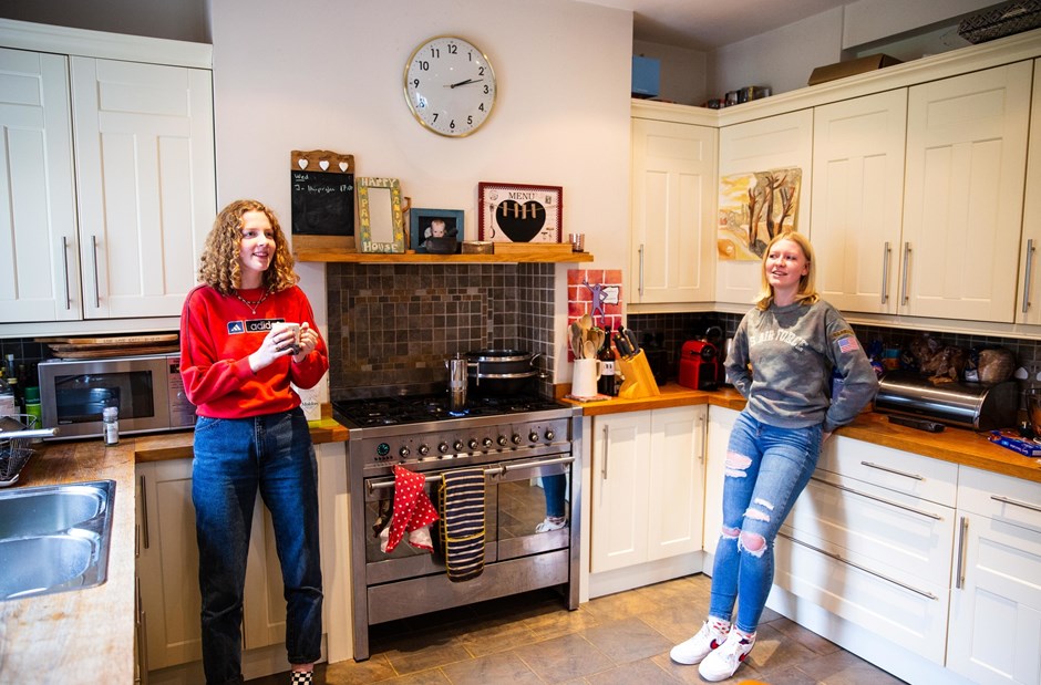 Two young women standing in a kitchen
