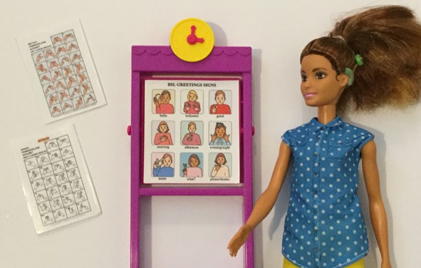 Barbie doll wearing cochlear implant teaching BSL