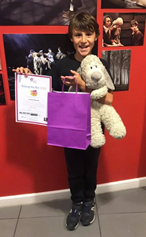 Boy at Raising the Bar event holding certificate and cuddly toy