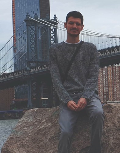 Onur Kerey sitting in front of a bridge.