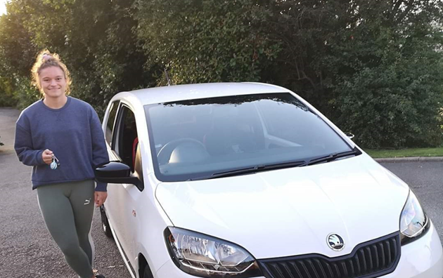 Teenage girl standing next to white car holding car keys