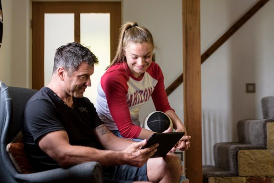 Father and daughter sitting together looking at an iPad.