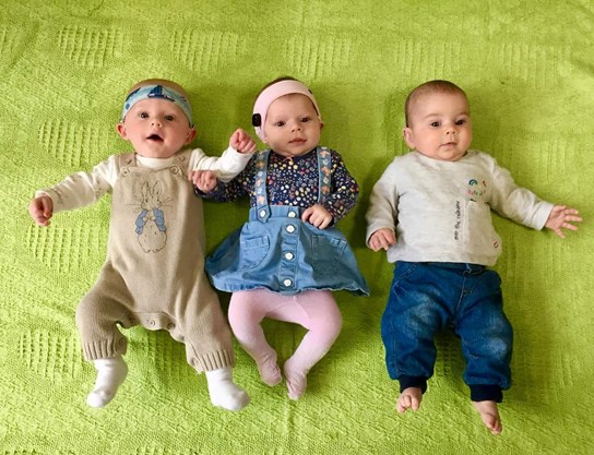 Three babies lying on a green blanket