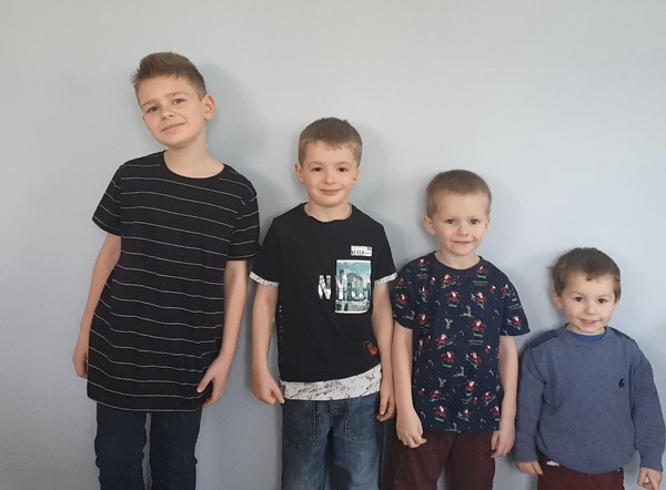 Four young boys lined up against a wall in height order