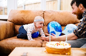 Dad and deaf toddler celebrating a birthday with cake and balloons