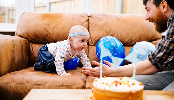 Dad and deaf toddler celebrating a birthday with cake and balloons