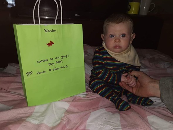 Small baby sitting next to paper bag