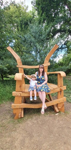 Mother and daughter sitting in a large wooden chair outside in the woods