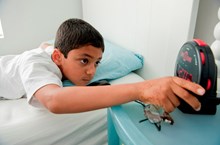 A boy adjusts his alarm clock.