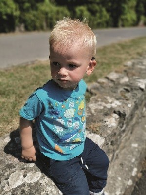 Mackenzie sitting on a wall outside.