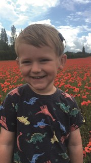 Rory standing in a field of poppies smiling.