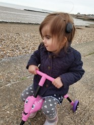 Photo of little girl on a bike with a cochlear implant