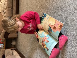 Little girl reading a copy of The Quest for the Cockle Implant