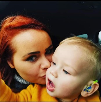 Photo of a mum kissing a little boy with hearing aids