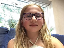 Poppy (10) wears glasses and smiles at the camera