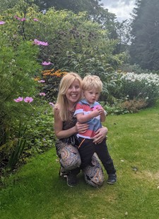 Photo of a mother and young son sitting outside on the grass