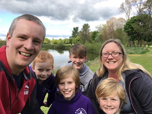 Family photo of two parents and four children outside by a lake.