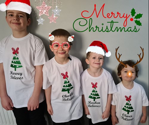Four young boys standing against a wall in height order wearing Christmas tshirts and hats
